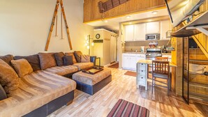 Un salón amplio con un sofá grande, una mesa de comedor y una cocina al fondo.