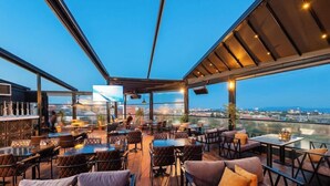 An outdoor seating area with tables and chairs, a bar, and a large TV screen. - Grand Abimo Hotel (Istanbul)