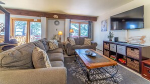Ein Wohnzimmer mit Ecksofa, Couchtisch, Fernseher und Kamin.