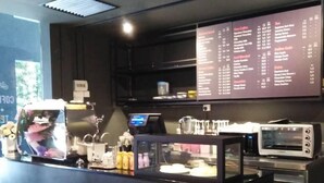 A modern cafe with a menu board, coffee machines, and stools. - Chariton Hotel Butterworth (Butterworth)