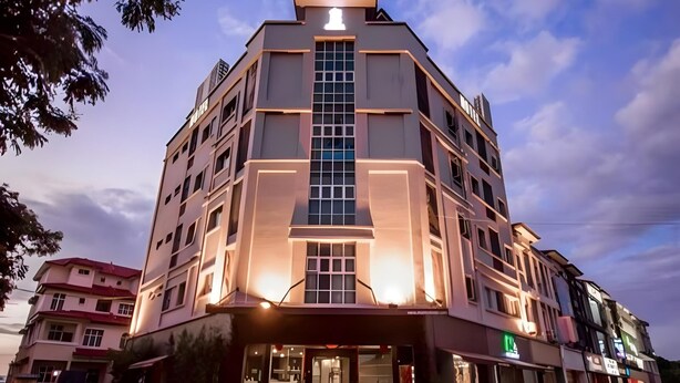 A multi-story hotel with a prominent central entrance, a parking area with several cars, and a clear sky in the background. - Chariton Hotel Butterworth (Butterworth)