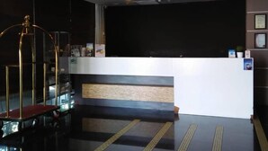A hotel lobby with a reception desk, a glass partition, and a red bench. - Chariton Hotel Butterworth (Butterworth)