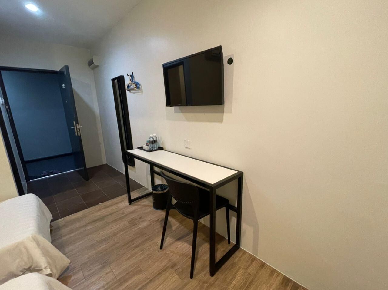 A small, compact room with a desk, chair, and a bed.