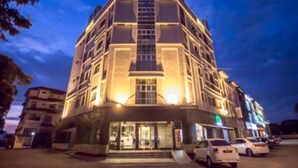 A multi-story hotel with a central entrance, a parking lot with several cars, and a clear sky. - Chariton Hotel Butterworth (Butterworth)