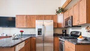 A modern kitchen with wooden cabinets, stainless steel appliances, a built-in oven, and a granite countertop. - Northstar - Ski Trail Condo (Truckee)