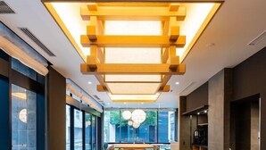 A conference room with a long wooden table, multiple chairs, and a modern ceiling light fixture. - Kazusaya Hotel (Tokyo)