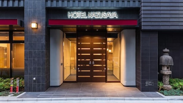 The exterior of Hotel Kazusaya with a modern design, featuring a prominent entrance with a wooden door and a red accent above the name. - Kazusaya Hotel (Tokyo)