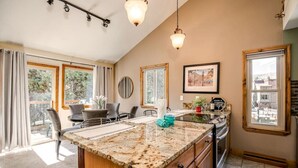 Una cocina con una isla grande, una zona de comedor con sillas y vistas al exterior.