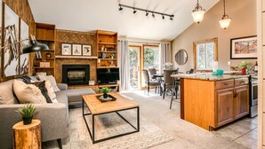 Una sala de estar amplia con chimenea, un comedor y una cocina con muebles de madera.