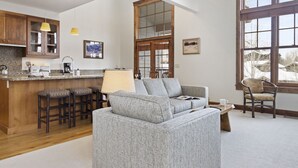 A modern kitchen with wooden cabinets, a bar stool area, and a large window providing natural light.