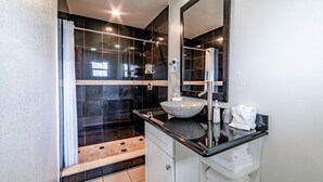 A modern bathroom with a glass-enclosed shower, a granite sink, and a large mirror. - Everglades City Motel - King Hotel Room (Everglades City)
