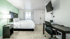 A hotel room with a bed, desk, chair, TV, and a window with curtains. - Everglades City Motel - King Hotel Room (Everglades City)