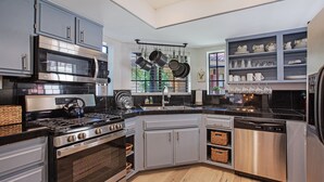 A modern kitchen with grey cabinets, stainless steel appliances, and a black countertop. - Oasis with 3rd Bedroom/Den, sleeps 6, 3 patios, adult and childrens bikes (Palm Springs)