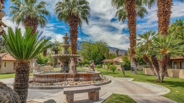 A landscaped garden with a central fountain, palm trees, and a stone bench. - Oasis with 3rd Bedroom/Den, sleeps 6, 3 patios, adult and childrens bikes (Palm Springs)