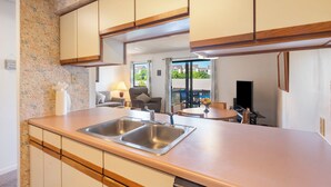 Una cucina moderna con due lavandini, mobili in legno e vista sull'area living.