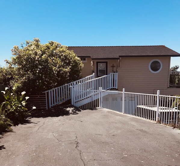 A single-story house with a front porch, a small circular window, and a white fence. - The Boathouse (Eureka)