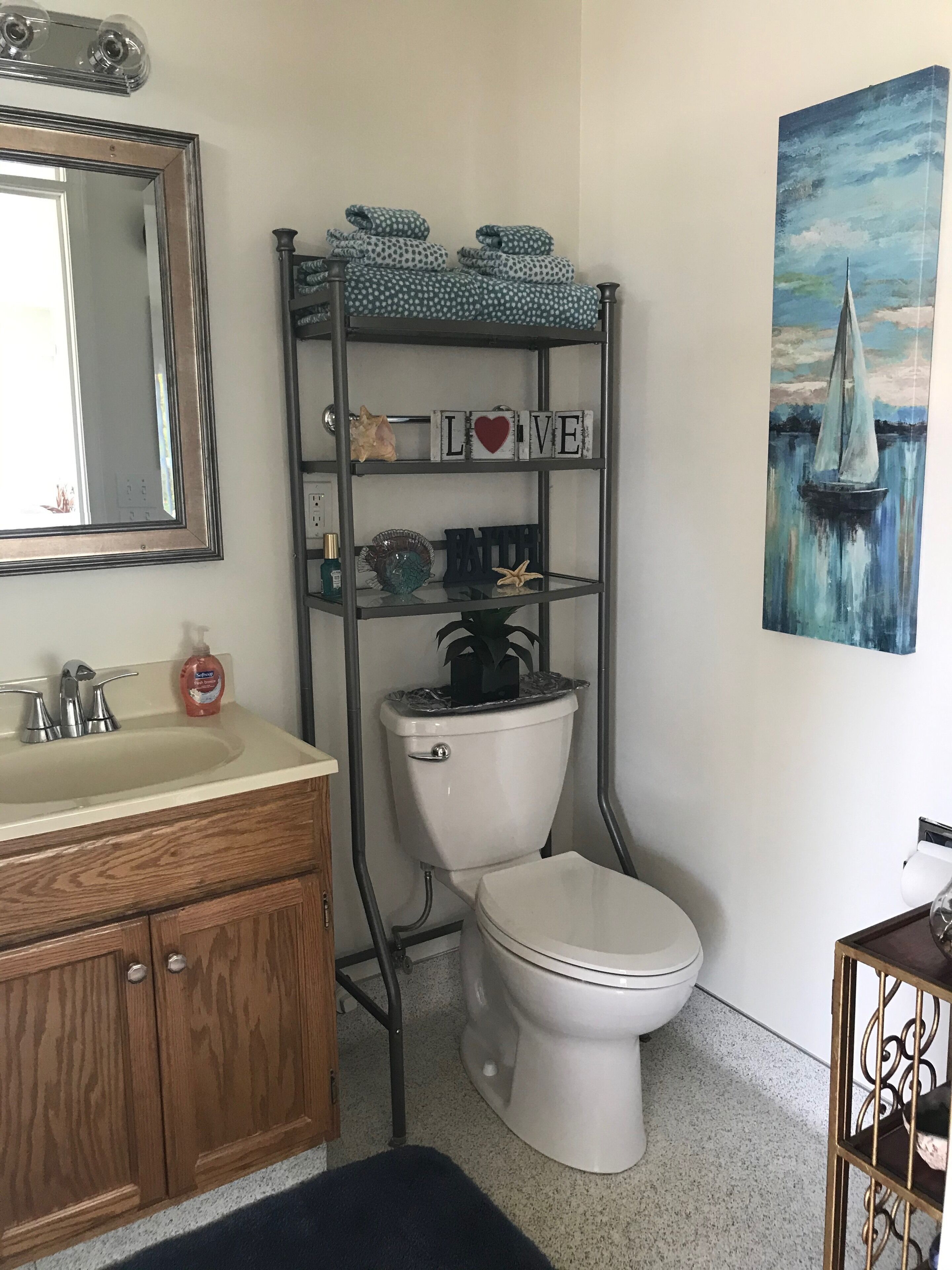 A bathroom with a toilet, sink, and a shelf with decorative items.