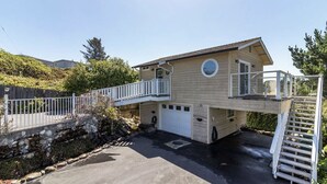 A two-story house with a front deck, a garage, and a staircase leading to an upper level. - The Boathouse (Eureka)