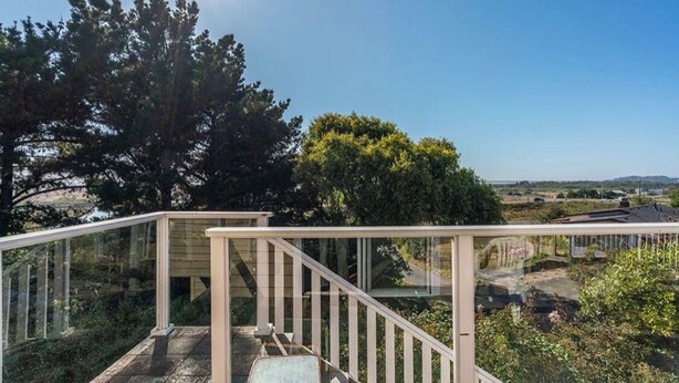 A balcony with a glass railing overlooking a garden and distant landscape. - The Boathouse (Eureka)