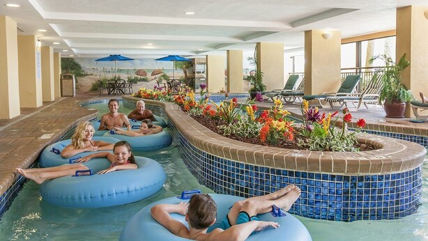 Uma área de piscina interna com boias azuis infláveis, borda de azulejos e um canteiro de flores.