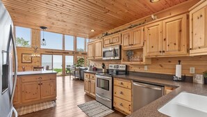 Eine geräumige Küche mit Holzausstattung, Edelstahlgeräten und großen Fenstern mit Blick ins Freie.