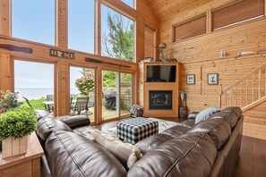 Ein geräumiges Wohnzimmer mit einer großen Ledersofa, einem Kamin und Blick ins Freie.