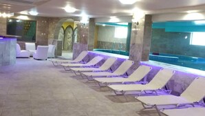 Un área junto a la piscina con sillones de descanso y una piscina.