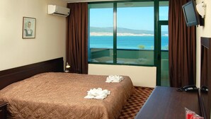 Habitación de hotel con cama, escritorio, televisión y vista al mar.