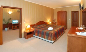 Ein Hotelzimmer mit Bett, Nachttischen, Fernseher, Kleiderschrank und Schreibtisch mit Telefon.