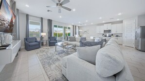A modern living room with a sofa, armchairs, a coffee table, and a television. - Serene Vibrant Villa with Games Room at Encore (Kissimmee)