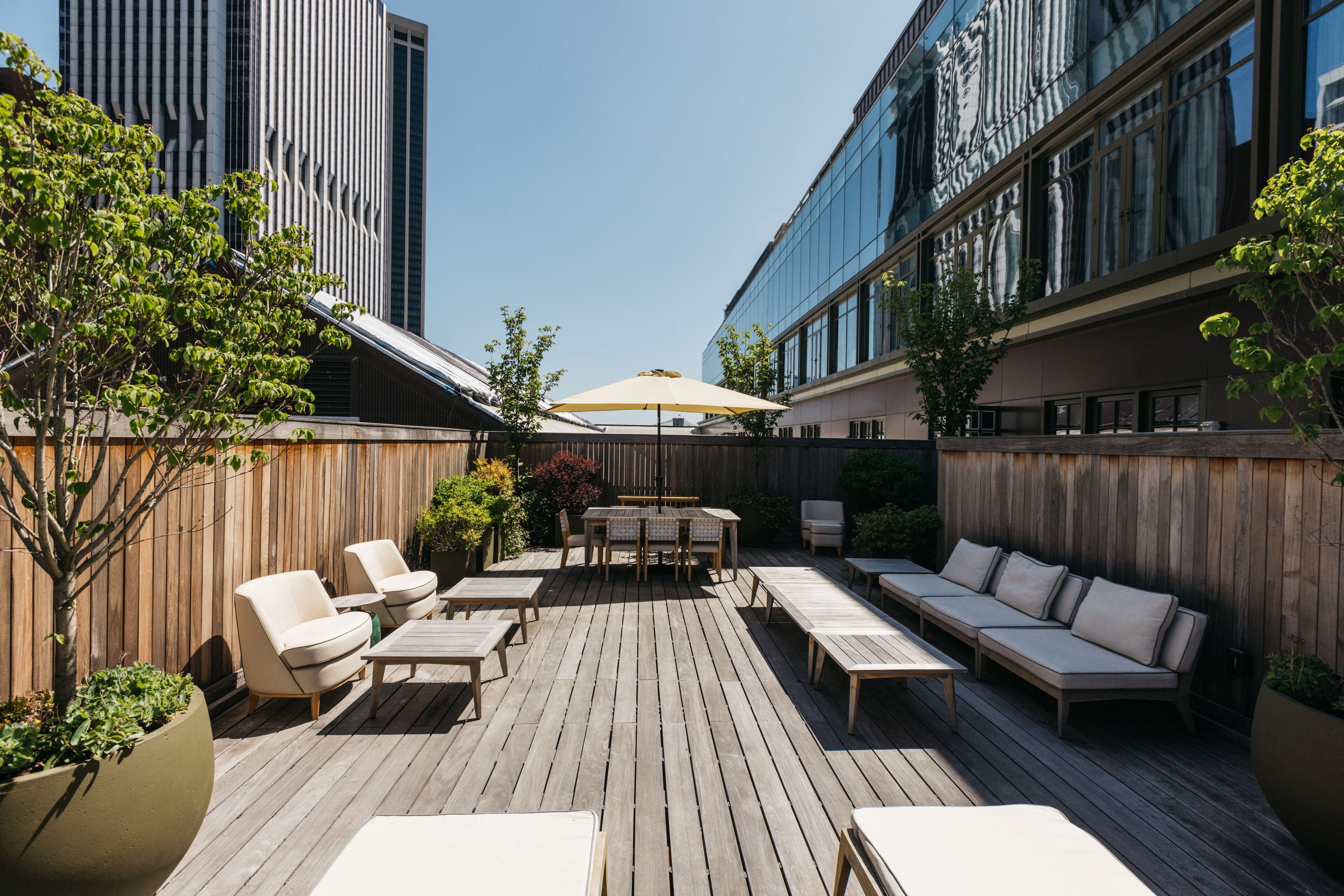 A wooden deck with outdoor furniture, a table, and an umbrella.