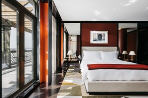 Ein Hotelzimmer mit einem großen Bett, Blick durch eine Glastür und einer roten Akzentwand.