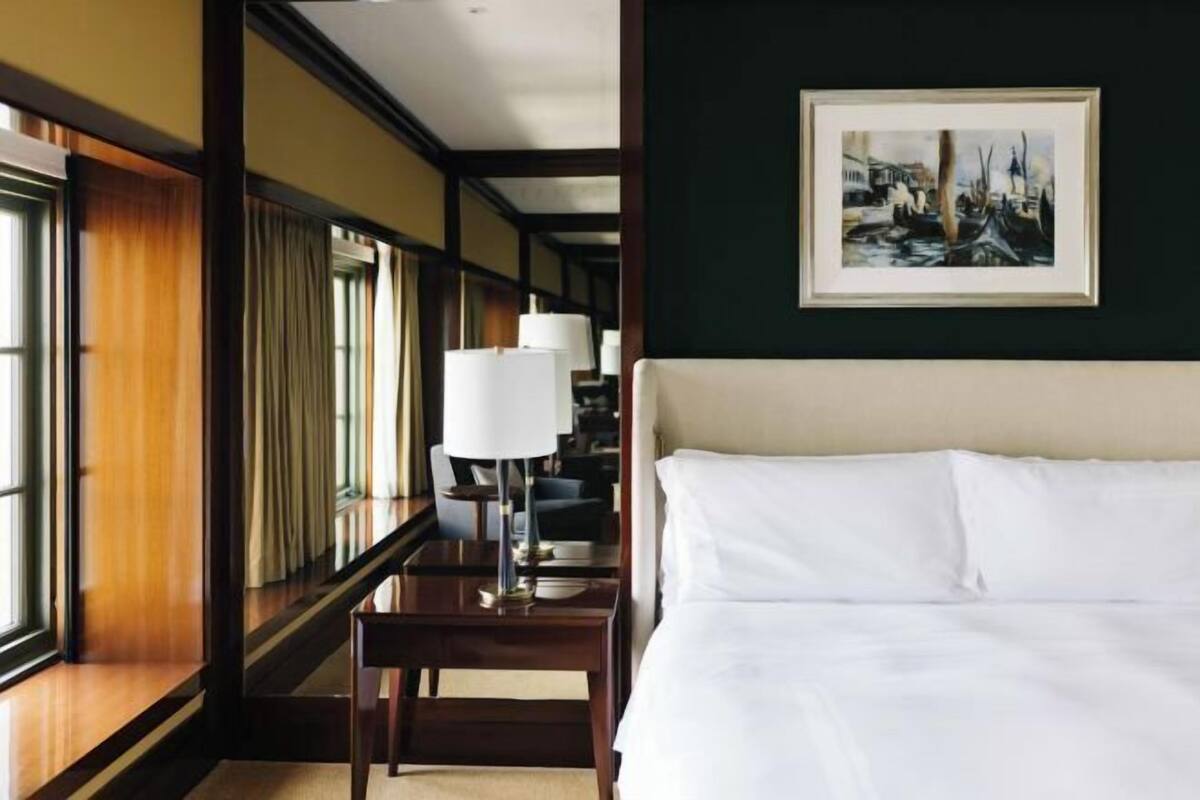 Une chambre d’hôtel avec un lit, une table de chevet, une lampe et un tableau encadré au mur.