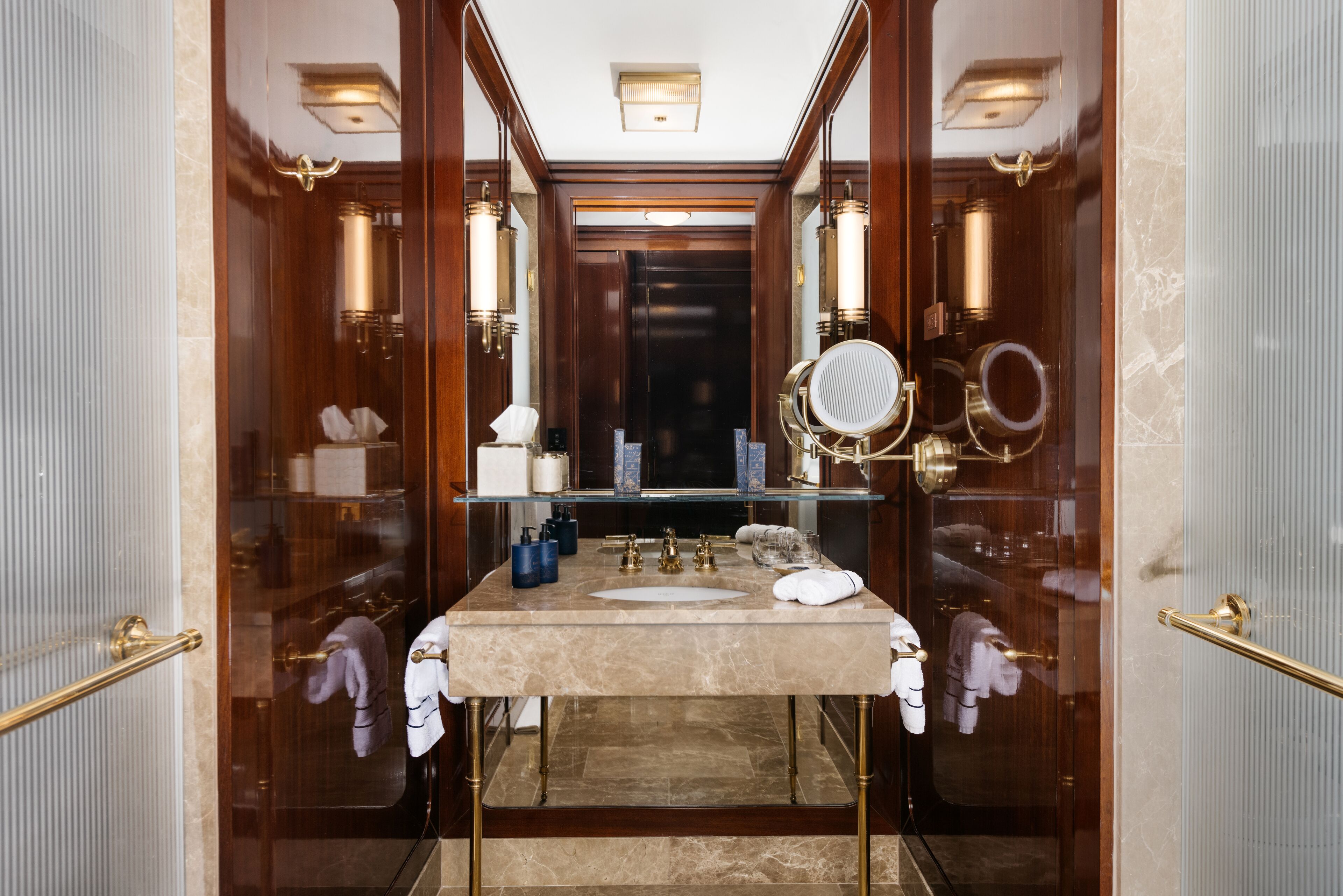 Une salle de bain luxueuse avec un lavabo en marbre, des robinets dorés et un grand miroir.
