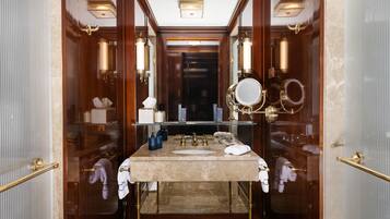 Une salle de bain luxueuse avec un lavabo en marbre, des robinets dorés et un grand miroir.
