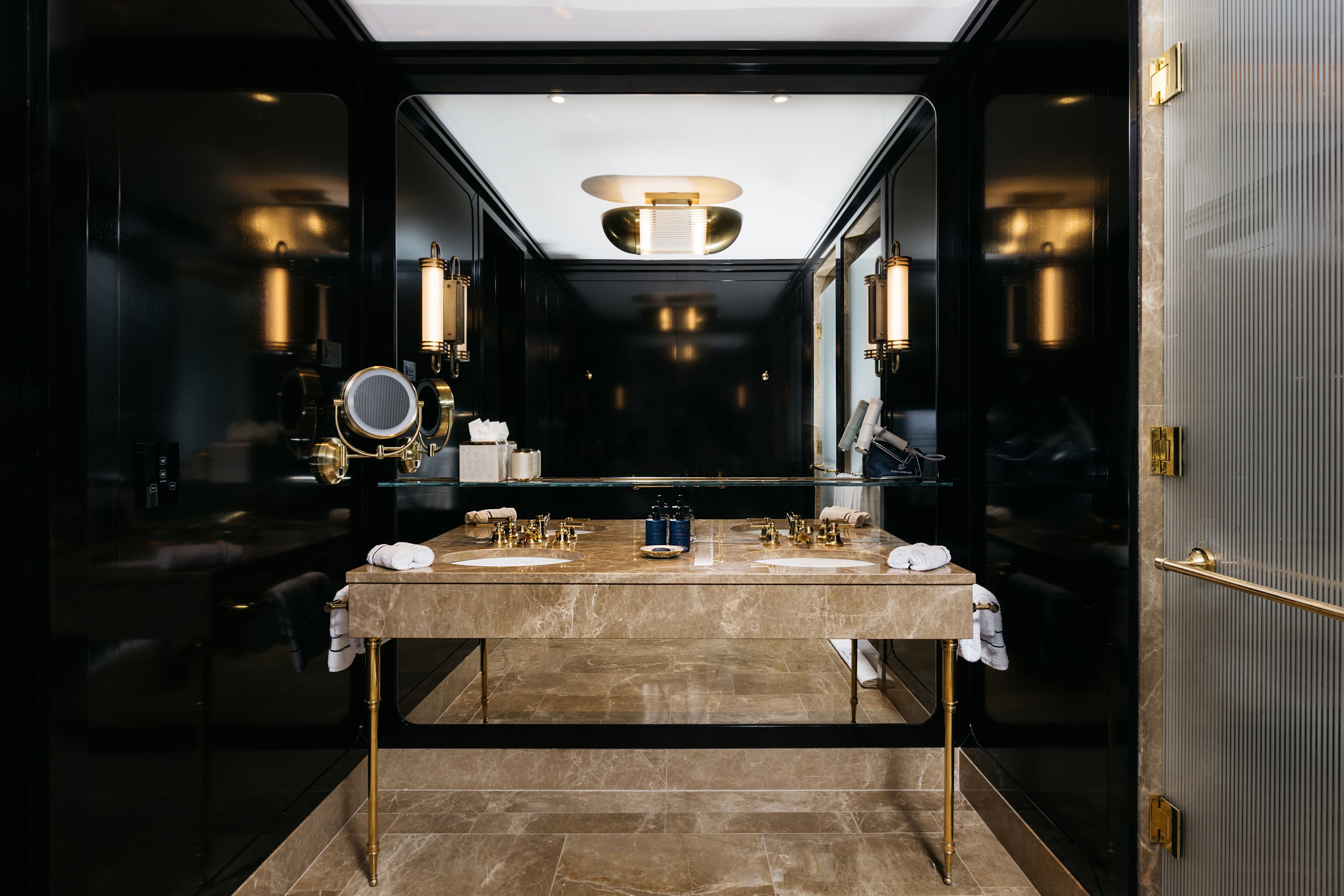 A luxurious bathroom with a large mirror, two sinks, and a modern light fixture.