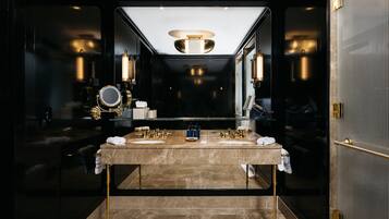 A luxurious bathroom with a large mirror, two sinks, and a modern light fixture.