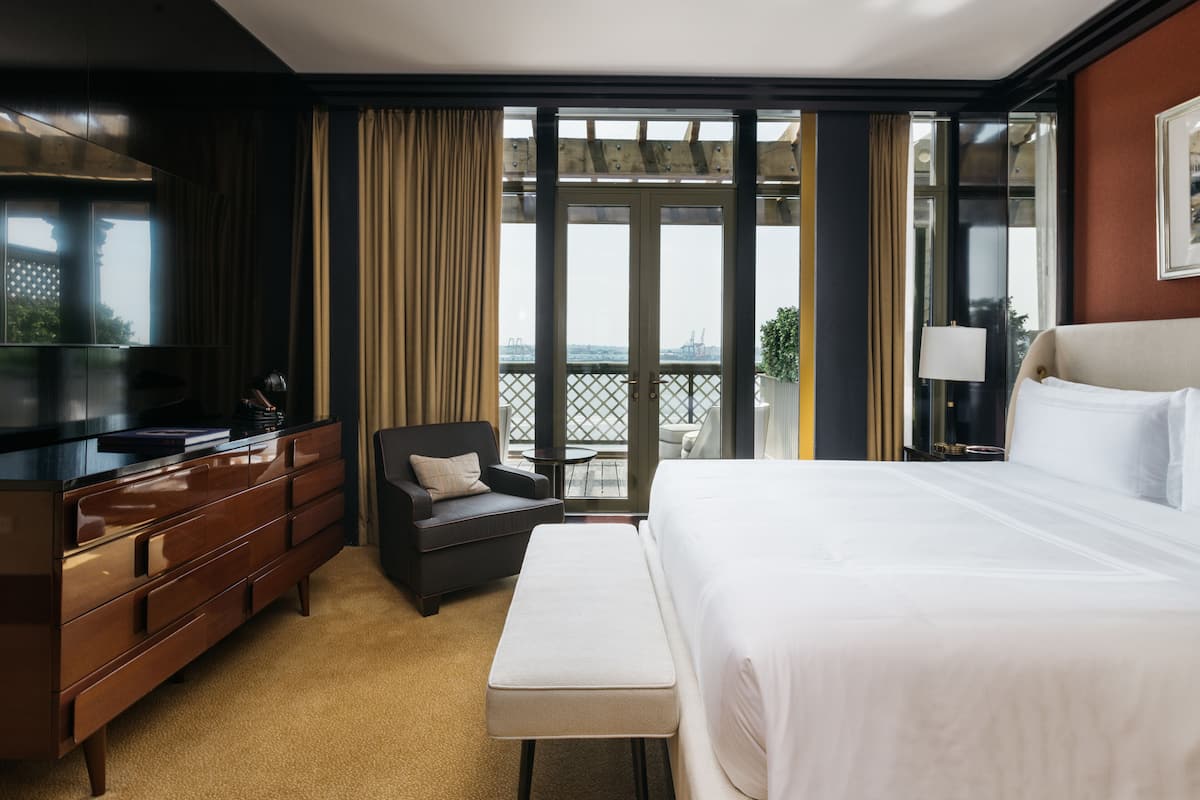 Une chambre d’hôtel avec un grand lit, une télévision, un canapé et un balcon avec vue.