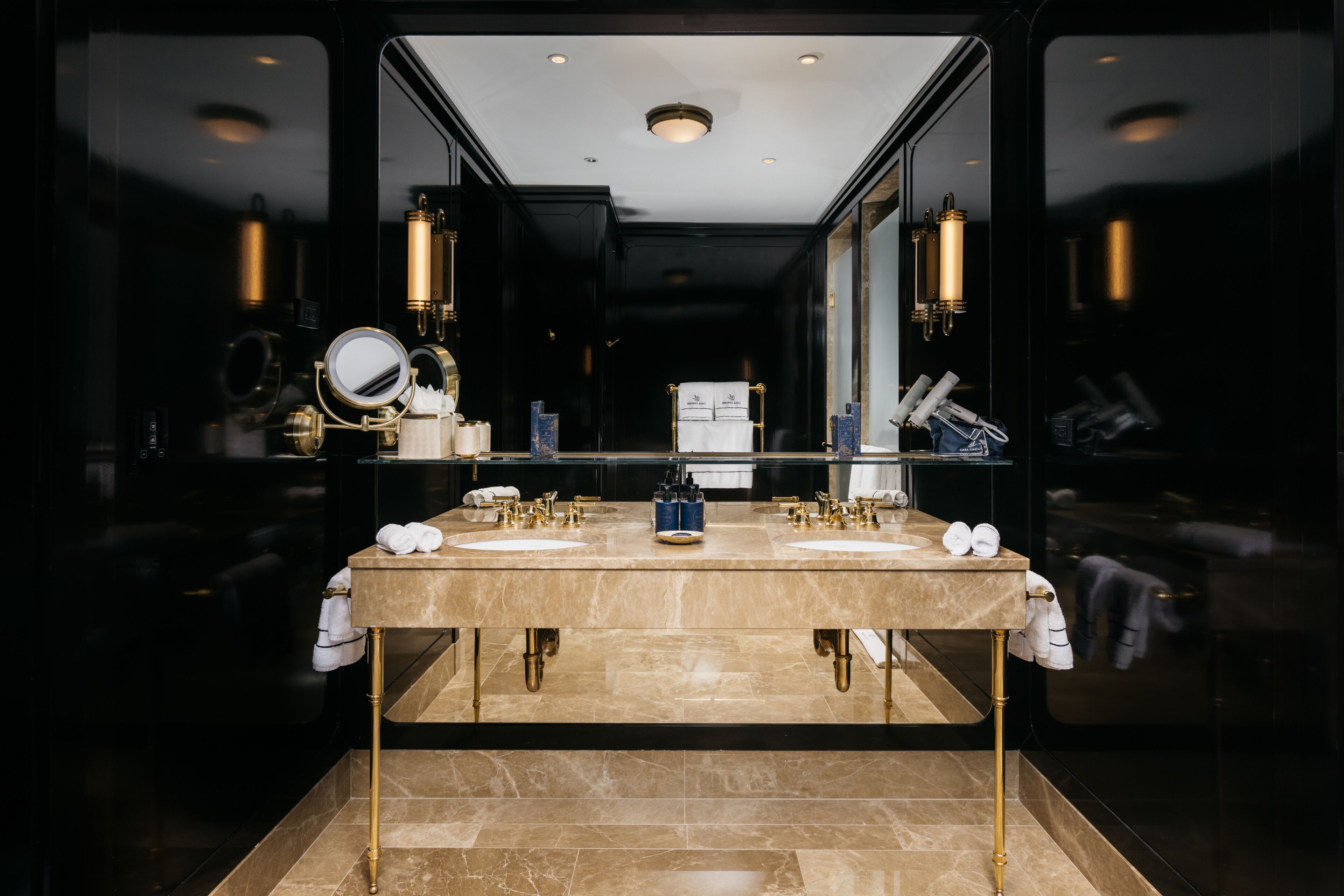 A modern bathroom with a large mirror, two sinks, and a vanity area.