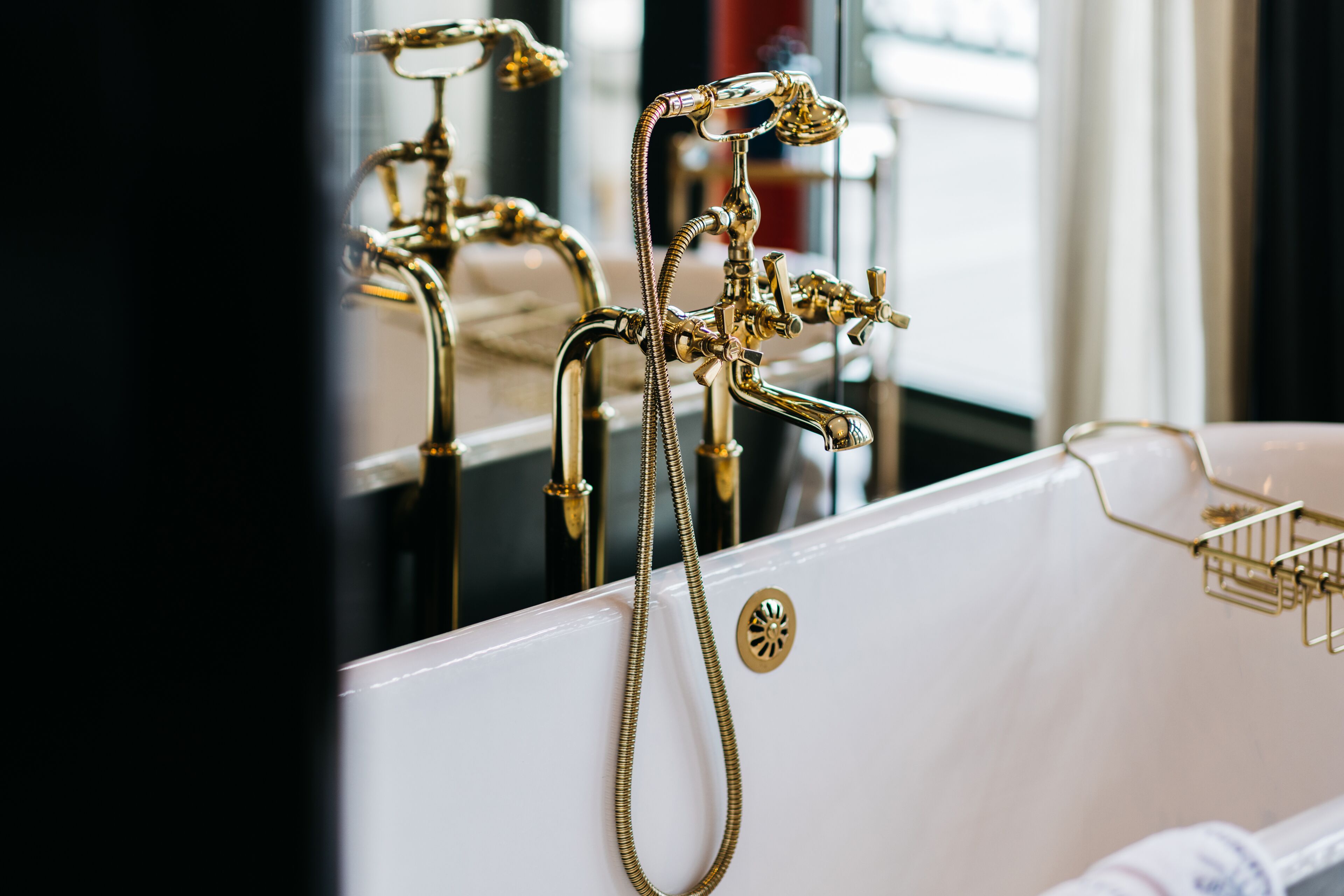 Una bañera con detalles dorados y una manguera de ducha.
