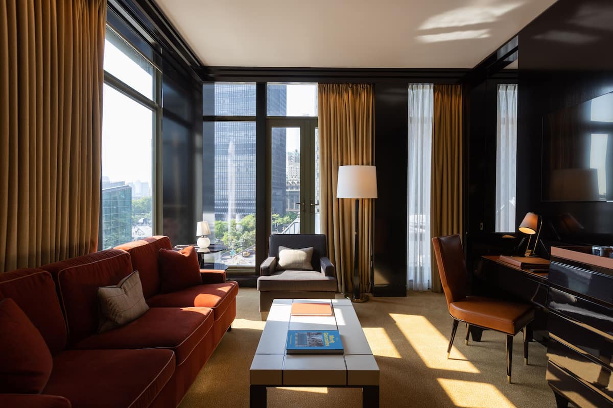 Une chambre d’hôtel moderne avec un canapé, un fauteuil et un piano.