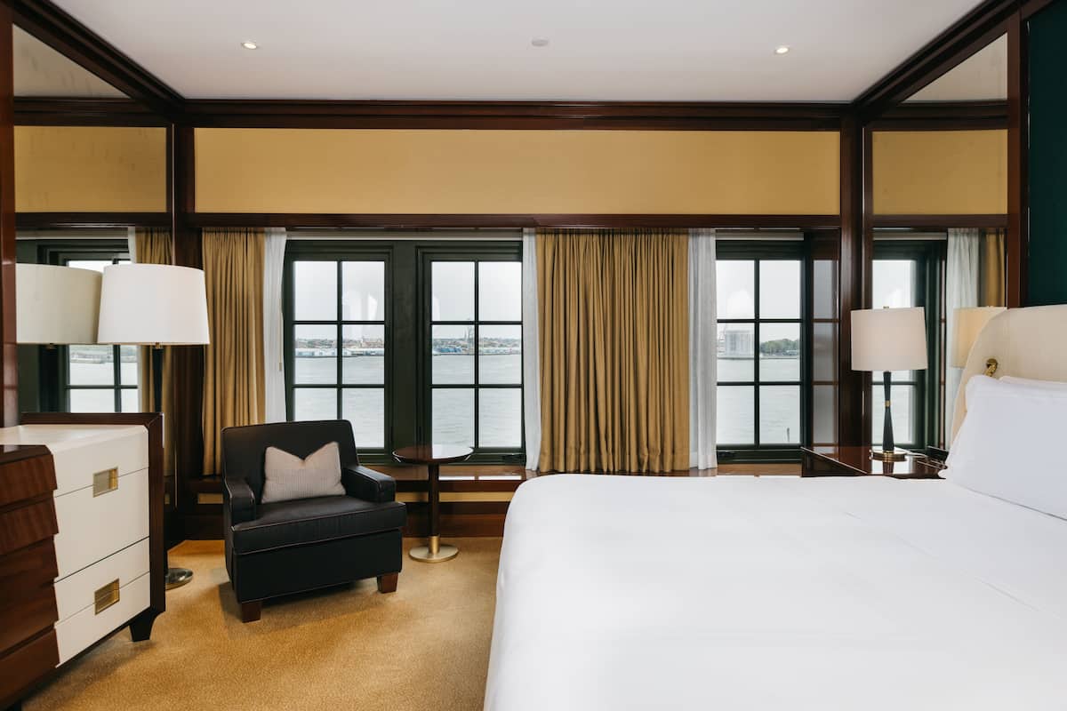Une chambre d’hôtel avec un grand lit, un bureau, une chaise et une vue sur l’eau.
