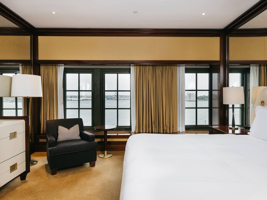Habitación de hotel con una cama grande, un escritorio, una silla y vista al agua.