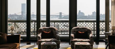 Una habitación con dos sillones mirando hacia una ventana grande que da a un puente y al paisaje urbano.