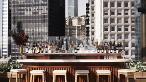 Een bar met uitzicht op de stad, met verschillende flessen en glazen op de toog.