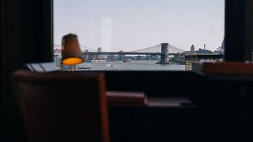 A view of a bridge from a room with a lamp on a table.