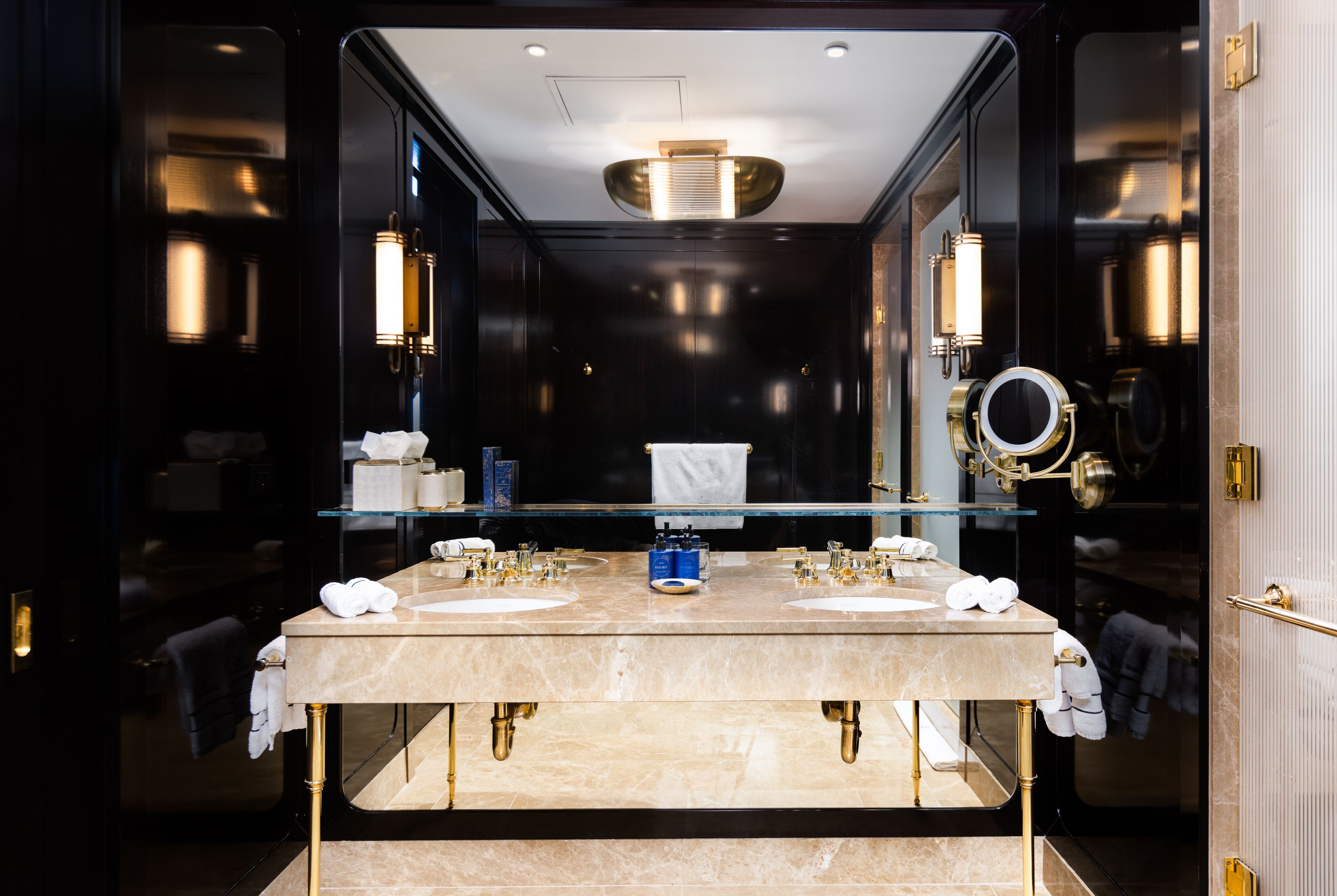 A modern bathroom with a large mirror, two sinks, and a glass partition.