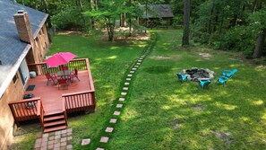 A backyard with a wooden deck, a fire pit, and outdoor seating. - Modern 4BR 3BA Ranch Home w Fenced-in Backyard (Cary)