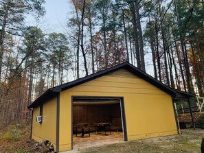 A yellow building with a black roof, a door, and a window. - Modern 4BR 3BA Ranch Home w Fenced-in Backyard (Cary)