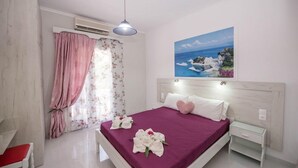 Ein Schlafzimmer mit Bett, Nachttisch, Stuhl und einem Gemälde einer Küstenlandschaft.
